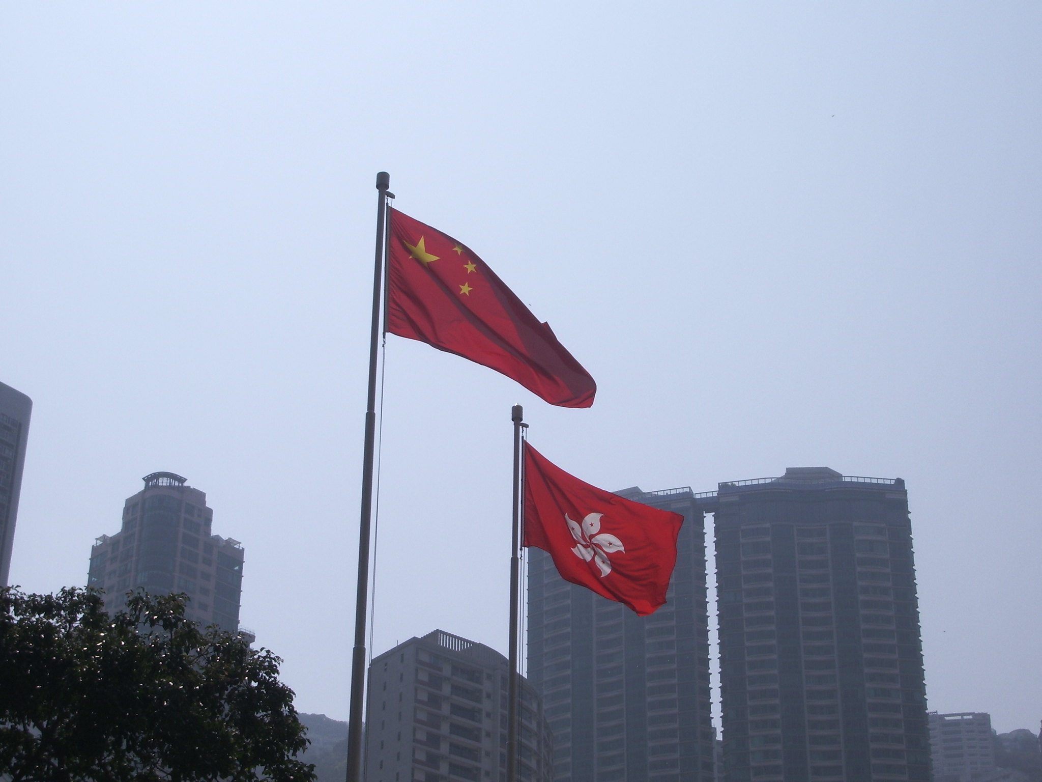 Na zdjęciu widać flagę Chińskiej Republiki Ludowej i flagę Hongkongu, w tle są budynki