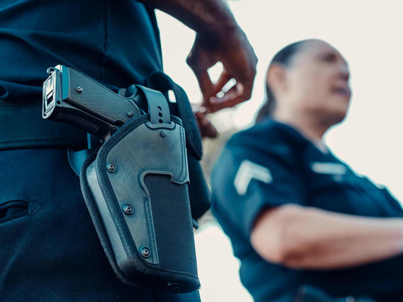 Na zdjęciu widać funkcjonariusza policji, który trzyma dłoń blisko broni podręcznej
