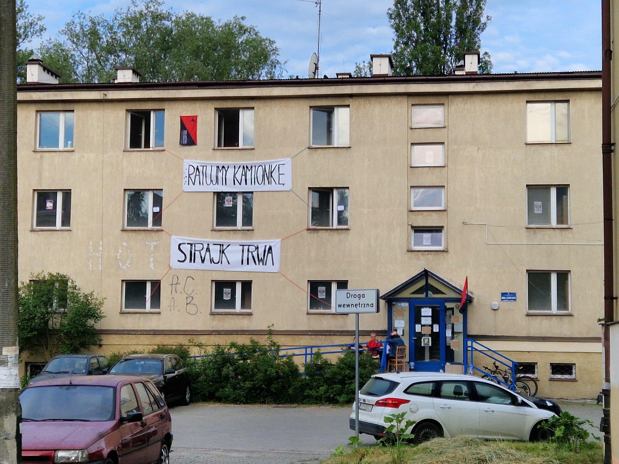 Fotografia przedstawia budynek domu studenckiego "Kamionka" z wywieszonymi banerami "Ratujmy kamionkę" i "Strajk trwa"